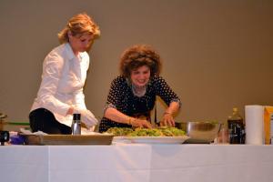 Two women preparing salad at a table