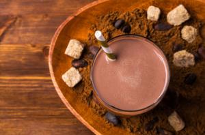 A bowl of chocolate milk with some brown sugar and nuts