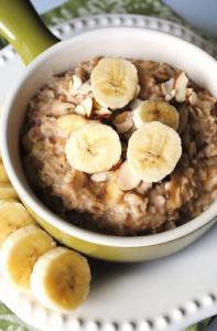 A bowl of oatmeal with sliced bananas and lemon.