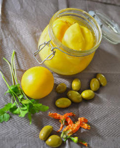 A jar of lemons and other fruits are on the table.