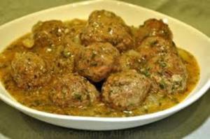 Meatballs in sauce on white plate.