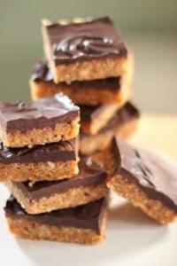 Chocolate-topped cookie bars stacked on plate.