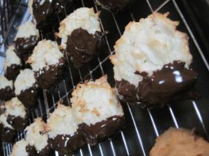 Chocolate-dipped coconut macaroons on cooling rack.
