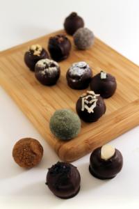 Assorted chocolate truffles on wooden board.