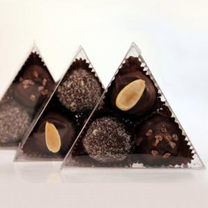 Three triangle shaped chocolate covered nuts in a plastic container.