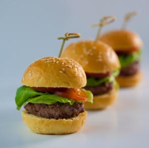 Three mini burgers with skewers in line.