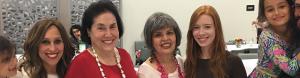 Three women wearing necklaces and smiling for a picture.