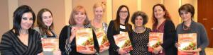 A group of women holding up brochures.