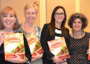 Four women holding up bags of food.
