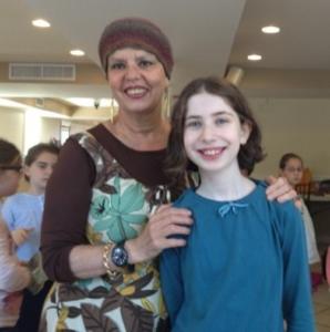Smiling woman and girl indoors with others.