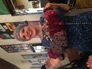 Smiling woman holding colorful knitted item.