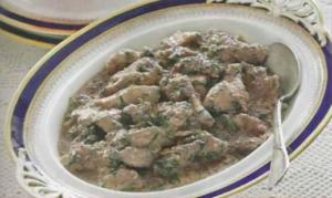 Creamy meat stew in ornate serving dish.