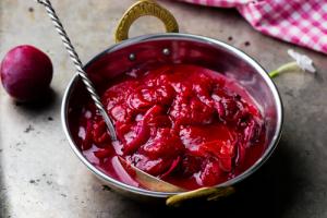A bowl of red sauce with a spoon in it.