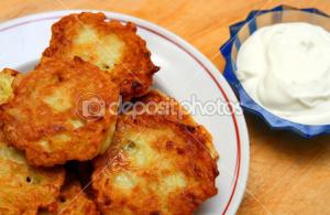 A white plate topped with potato cakes next to a bowl of dip.