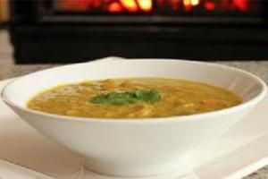 A bowl of soup with green garnish on the side.