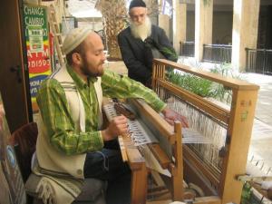 A man sitting on top of a bench weaving.
