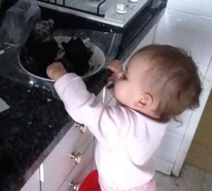 Toddler reaching for chocolate cake on counter.