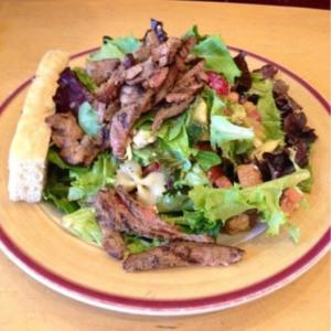 Steak salad with bread on plate.