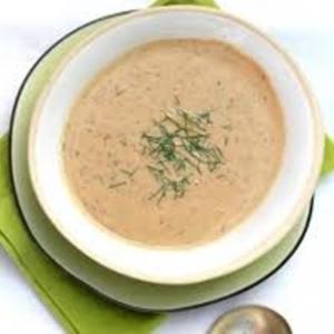 Creamy soup with herbs in white bowl.