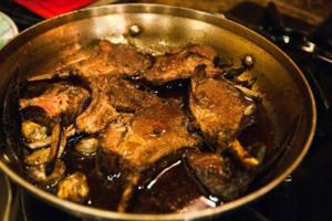 Lamb chops cooking in a pan.