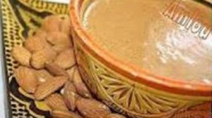 A bowl of peanut butter and almonds on the table.