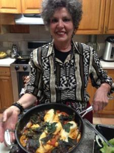 Woman holding pan of cooked food.