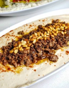 Hummus topped with spicy grpundf meat and pine nuts