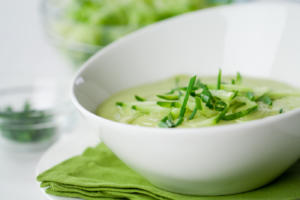 A bowl of soup with green onions in it.