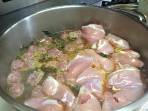 A pan of meat and vegetables cooking in sauce.