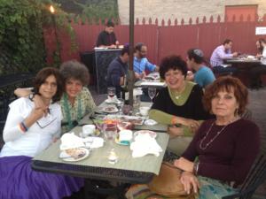 Four women smiling around outdoor dinner table