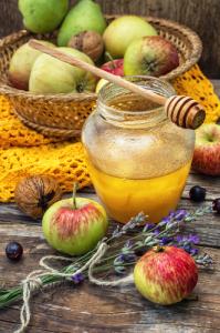 A jar of honey and some apples on the table