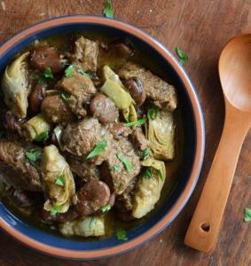 A bowl of food with meat and vegetables.