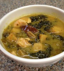 A bowl of soup with chicken and broccoli.