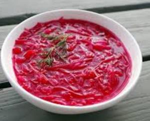 A bowl of soup with red cabbage and herbs.