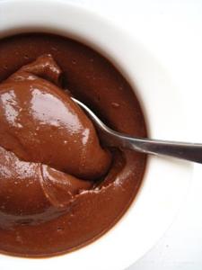 A spoon in chocolate spread on top of a bowl.