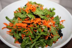 A plate of salad with carrots and greens.