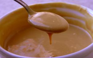 A spoon is in the bowl of some kind of liquid.