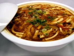 A bowl of soup with noodles and herbs.