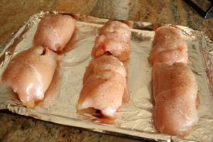 A tray of chicken wrapped in bacon on top of a table.