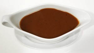 A bowl of sauce is sitting on the table.