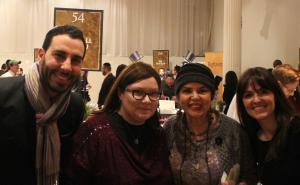 Three people posing for a picture in front of a painting.
