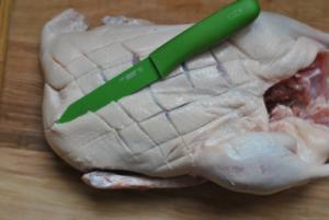 Raw scored duck with green-handled knife