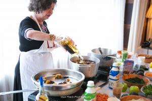 A woman in an apron cooking food on top of a stove.
