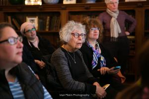 A group of people sitting in chairs and looking at something.
