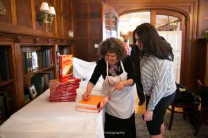 Two women looking at a book on the table.