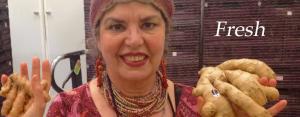 A woman wearing a hat and jewelry poses for the camera.