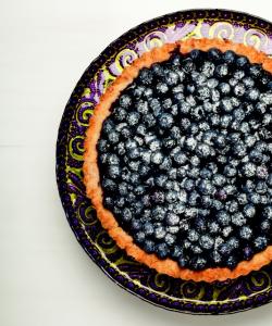 A plate with blueberries on it sitting on top of a table.