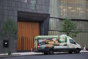 A van with a picture of people on it parked in front of a building.