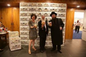 Three people posing for a picture in front of a wall.