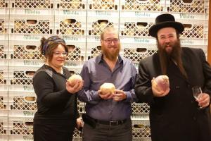 Three people holding apples in front of a wall.
